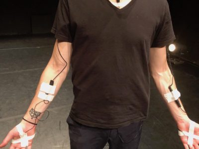 Un artiste équipé de capteurs sonores sur l'intérieur des bras