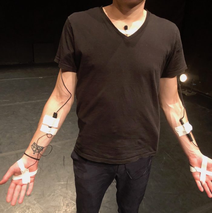 Un artiste équipé de capteurs sonores sur l'intérieur des bras